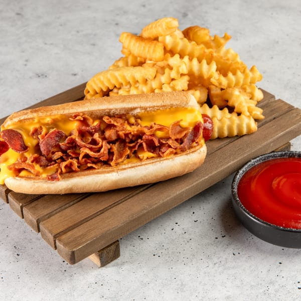 Stewart's Drive-In bacon cheesedog with crinkle-cut fries and a side of ketchup on a wooden board.