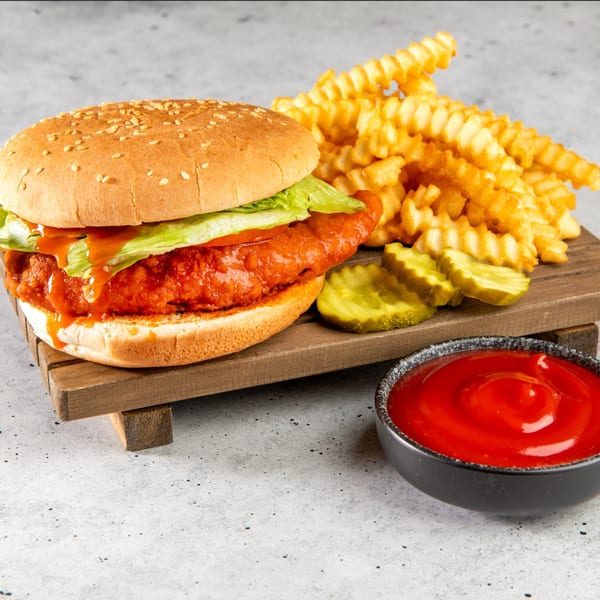 Stewart's Drive-In spicy chicken sandwich with lettuce, crinkle-cut fries, pickles, and ketchup.